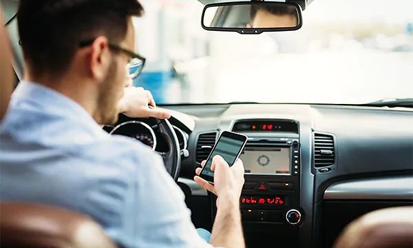 Tvättmaskin med wifi: En man sitter i en bil och fjärrstyr sin tvättmaskin med telefonen.