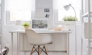 Ett hemmakontor i vitt med en vit laptop från Acer på ett vitt skrivbord. 