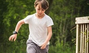 En pojke i full fart som springer med en Xplora X5-smartklocka på armen. 