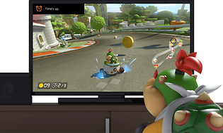 Nintendo switch med bild på ett monster som sitter framför en skärm som visar ett TV-spel.