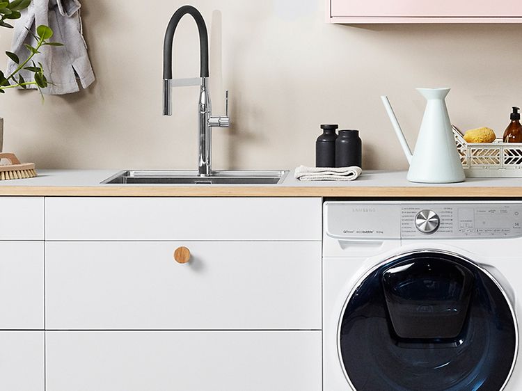 Vit tvättstuga med grå bänkskiva i linoleum, tvättmaskin och torktumlare.