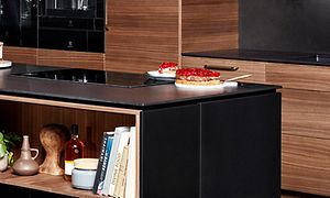 Svrat bänkskiva i Dekton på en köksö med hyllor på sidorna.