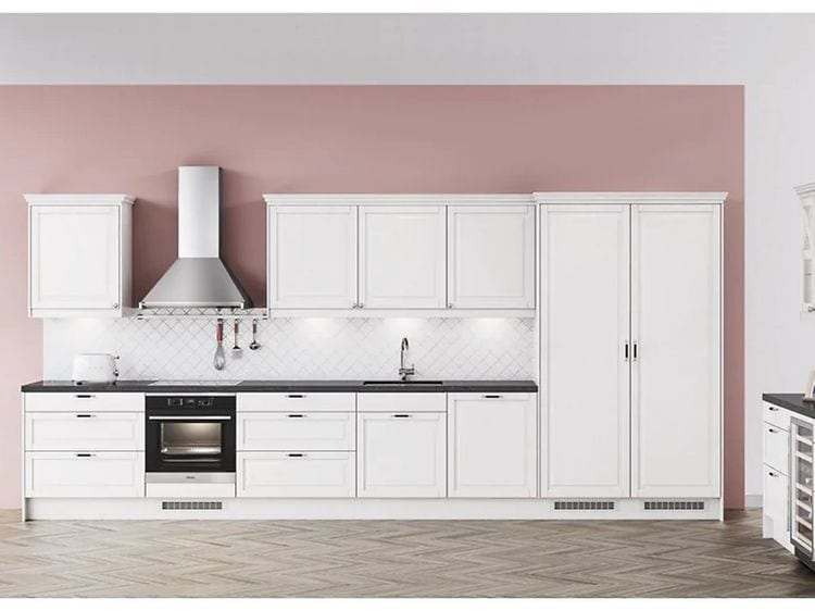 Vitt kök med silverfärgad vägghängd köksfläkt och rosa tapeter. 