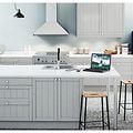 Ljust kök med en vit väggmonterad köksfläkt och ett blått kylskåp från Smeg och köksö med stolar. 