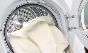 Bild på en tvättmaskin med öppen dörr och en massa vit tvätt inuti. 