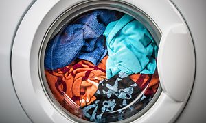 Tvättmaskin som är full med tvätt i olika färg. 