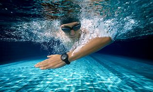 Bild under vatten på en manlig simmare i simglasögon och badmössa med en svart Huawei Watch 3 på armen.