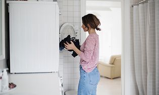 En kvinna fyller sin tvättmaskin med tvätt