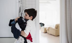 pojke som tar tvätt ur tvättmaskinen