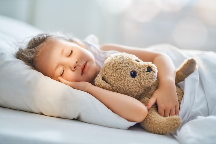 Flicka som sover med sin nalle