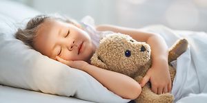 Flicka som sover med sin nalle