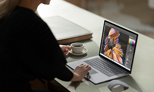 Kvinna som använder en Microsoft Surface-laptop på skrivbord med en kopp kaffe bredvid.
