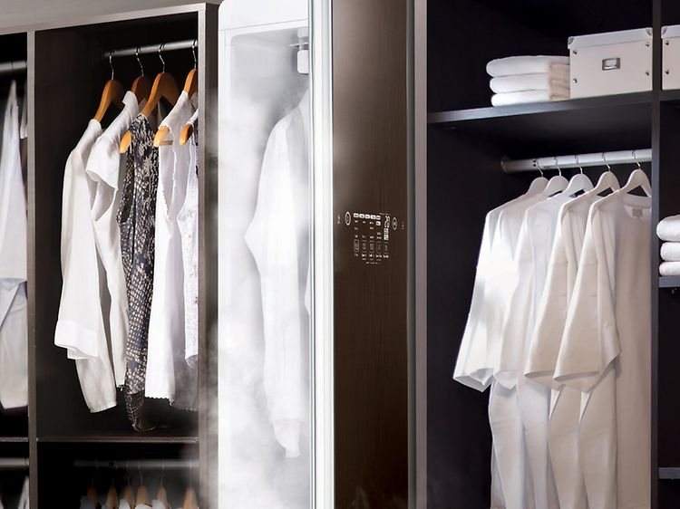 Torkskåp i en klädkammare med en massa vita kläder som är vikta eller hänger. 