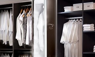 Torkskåp i en klädkammare med en massa vita kläder som är vikta eller hänger. 