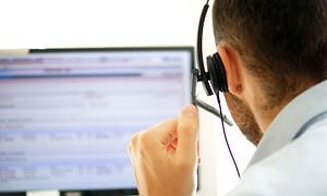 Kundtjänstpersonal med hörlurar som sitter vid en dator