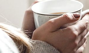 Närbild på en kvinnas händer som håller i en te mugg.