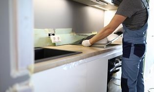 Man som installerar en integrerad spishäll i ett kök i en träbänkskiva. 