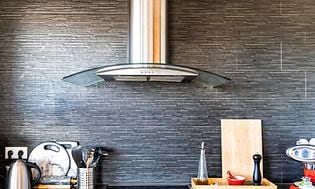 Integrerade vitvaror med stilren väggmonterad köksfläkt i stål. 