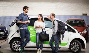 MDA-Electric car chargers- Three people standing in forn of an electric car in a parking house (1)