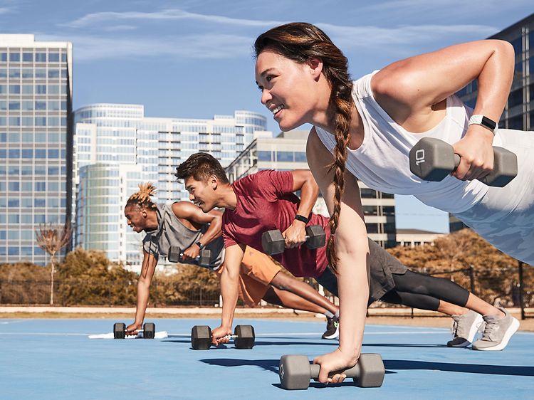 Fitbit Charge 5 on the arms of three people working out