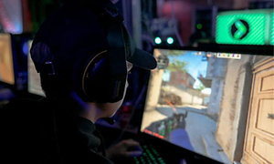Pojke som sitter framför en dator och spelar med ett headset på sig.