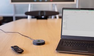 IRIS videokonferenssystem på ett bord i ett mötesrum, bredvid en bärbar dator.