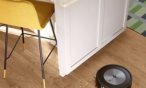 iRobot som dammsuger upp brödsmulor på ett köksgolv.