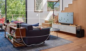 Vardagsrum med en soffa mitt i rummet och en TV med sonos beam 2 soundbar och surroundeffekt.