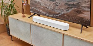 TV på tv-bänk med en vit sonos beam 2 under. 