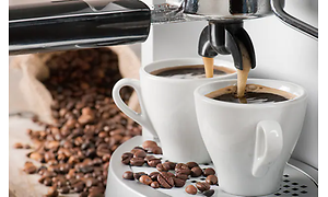 Espressomaskin som brygger två koppar espresso samtidigt med kaffebönor som ligger runt omkring.