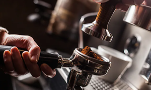 En hand som sätter in en filterhållare fylld med kaffe i espressomaskinen.