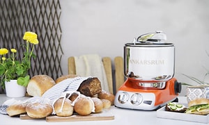 Köksmaskin från Ankarsrum med en massa olika sorter nybakat bröd på bordet bredvid. 