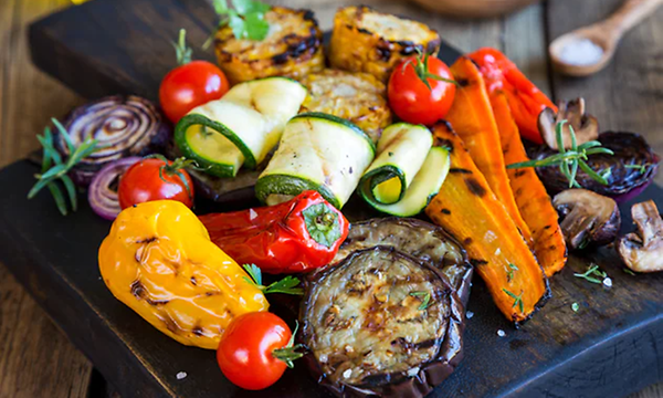 Olika sorters grillade grönsaker på ett svart fat som zuccini, paprika, majs mm.