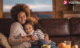 Mother and daughter in the sofa looking at smartphone