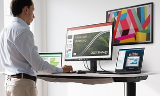 Man jobbar på hemmakontor stående vid ett skrivbord med Lenovo ThinkPad på. 
