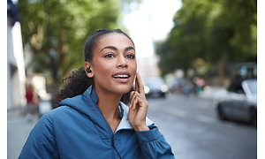 Kvinna pratar i telefon med Jabra Elite 7 i öronen när hon är i farten