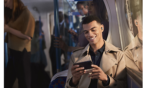 Man på tunnelbana som ser på video med Jabra Elite 7 i öronen