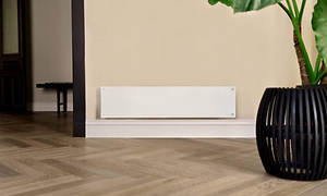 Vitt långsmalt element från Mill placerat på en beige vägg med en stor växt bredvid.