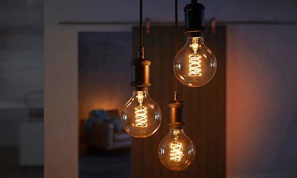 Tre Philips Hue-glödlampor som hänger med glödande filament. 