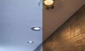 Philips Hue Adore spotlights i ett tak. Bilden delad i två där ena sidan visar kallt ljus och andra sidan varmt.  