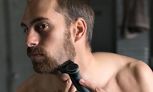 Man som trimmar sitt skägg med en Philips OneBlade Pro