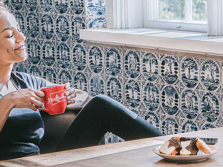Kvinna som dricker kaffe från en kopp och kaffemaskin på ett bord