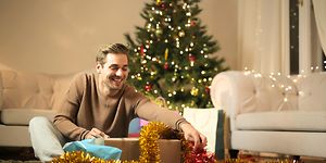 En man öppnar en julklapp som han fått av sin partner - Julklappar till pojkvän