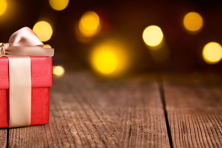 Julklappspel - En röd julklapp med guld rosett mot en mörk bakgrund