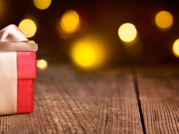 Julklappspel - En röd julklapp med guld rosett mot en mörk bakgrund