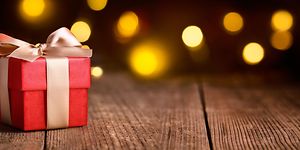Julklappspel - En röd julklapp med guld rosett mot en mörk bakgrund