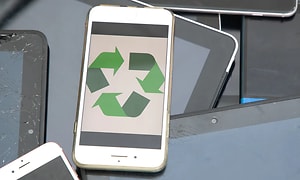 Vit mobiltelefon med en grön återvinningssymbol