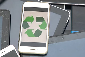 Vit mobiltelefon med en grön återvinningssymbol