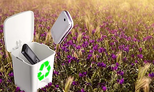 En blomsteräng och två mobiltelefoner på väg ner i en återvinningslåda