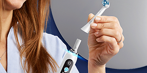 Kvinna som byter borsthuvud på en Oral-B eltandborste.